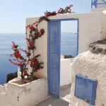 Rustic and traditional doorway to a Greek holiday villa festooned with flowers.