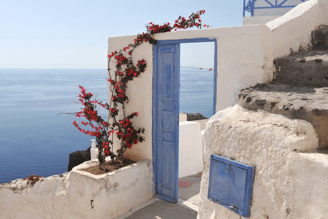 Rustic and traditional doorway to a Greek holiday villa festooned with flowers.